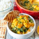 a small bowl of butternut squash curry over rice with a wedge of naan bread on the side