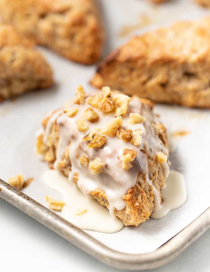 a vegan banana scone drizzled with maple glaze and sprinkled with nuts 