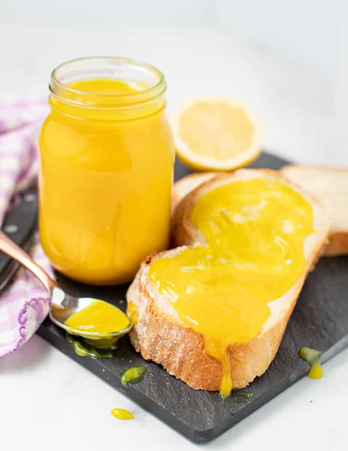 a jar of vegan lemon curd and a slice of bread spread with it