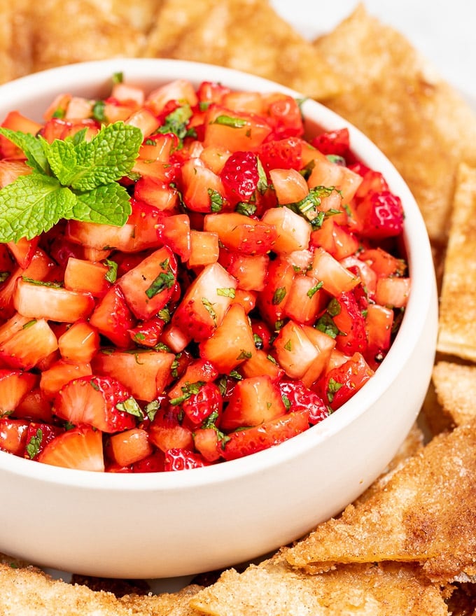 a close up picture of strawberry salsa in a bowl garnished with mint 