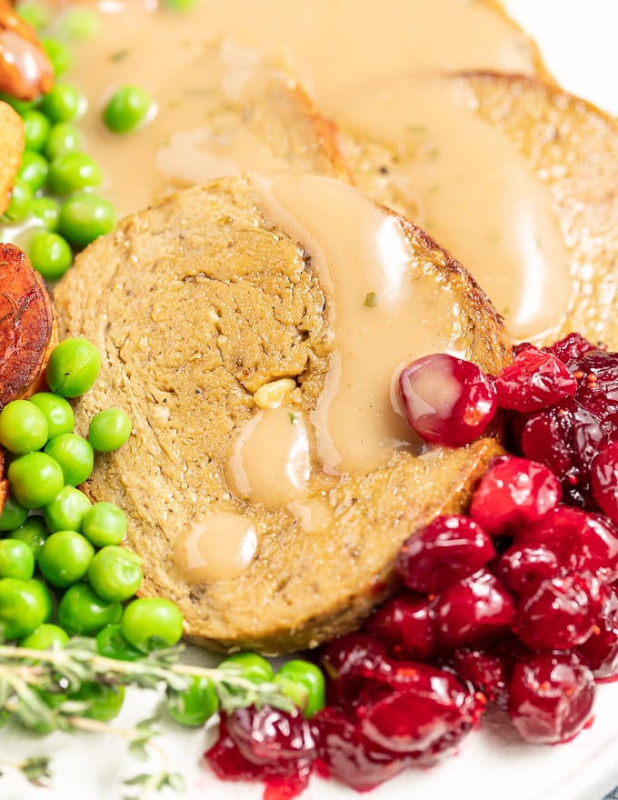 close up of sliced vegan roast, gravy and cranberry sauce 