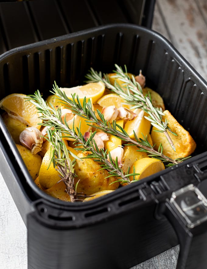 potatoes with lemon, garlic and rosemary in an air fryer basket 