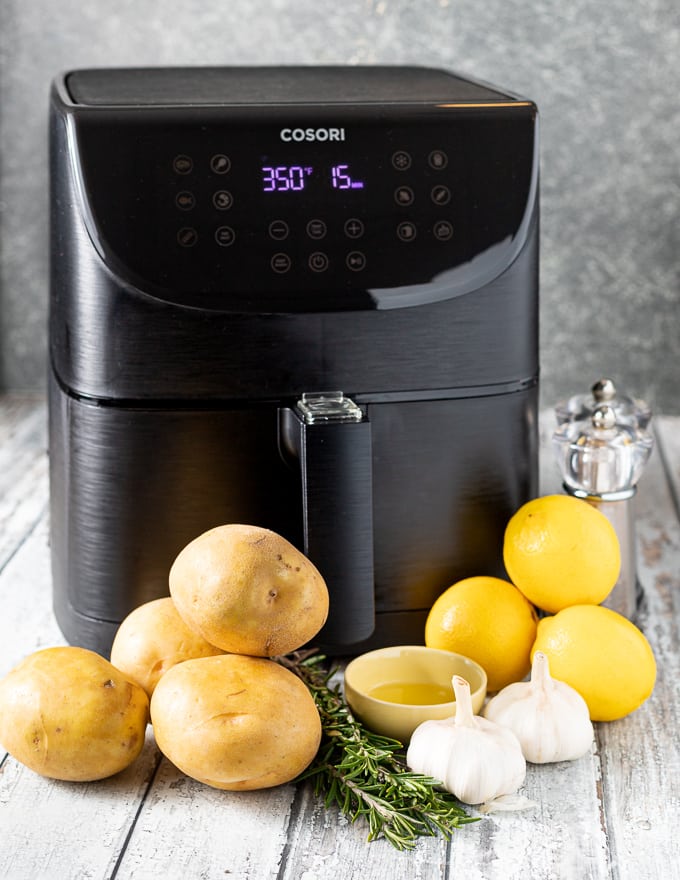 a Cosori air fryer with the ingredients for Lemon Garlic Air Fryer Roasted Potatoes