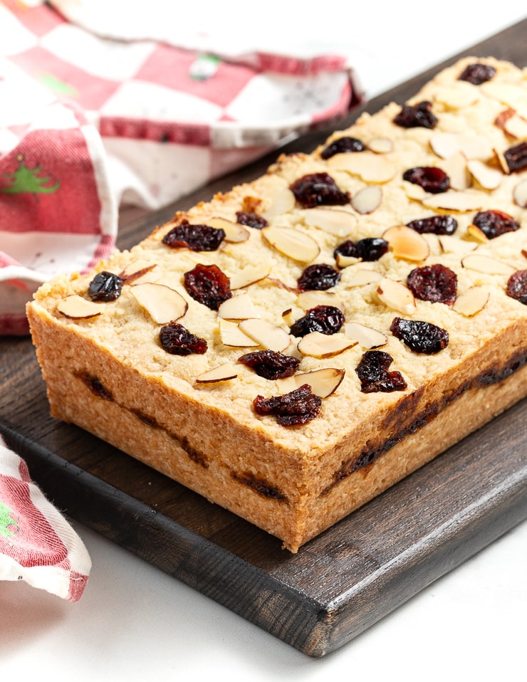 A large bar of Christmas shortbread on a dark brown cutting board