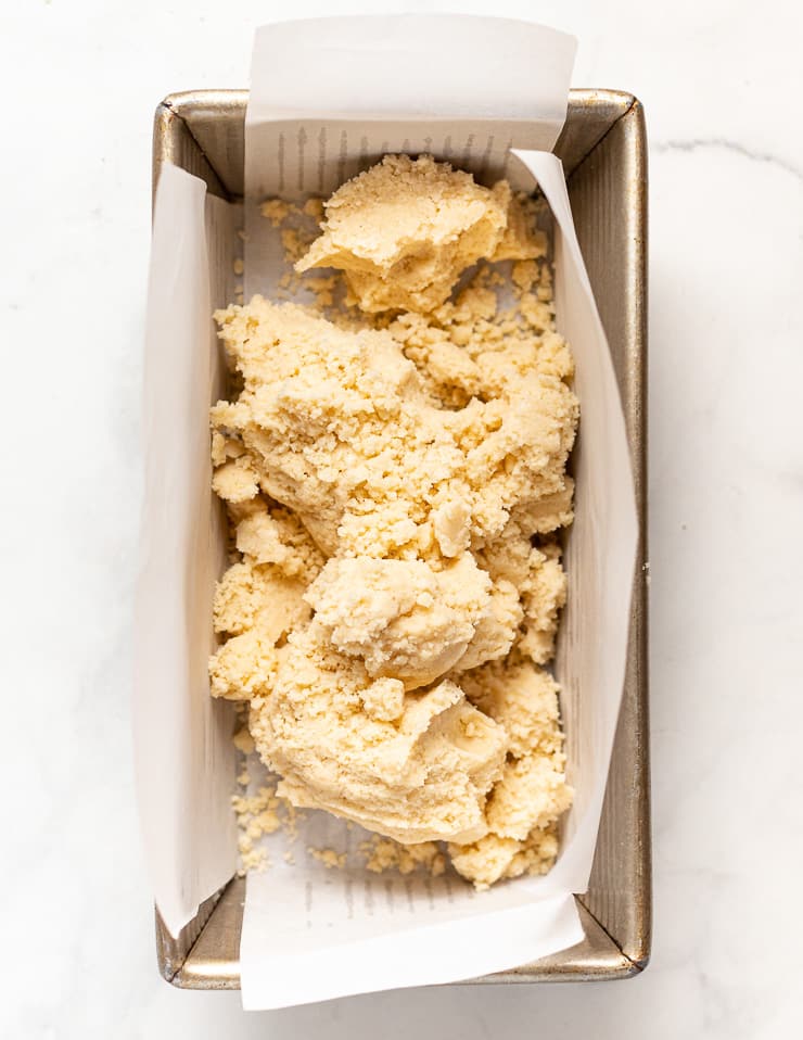 crumbly vegan shortbread dough in a lined loaf pan