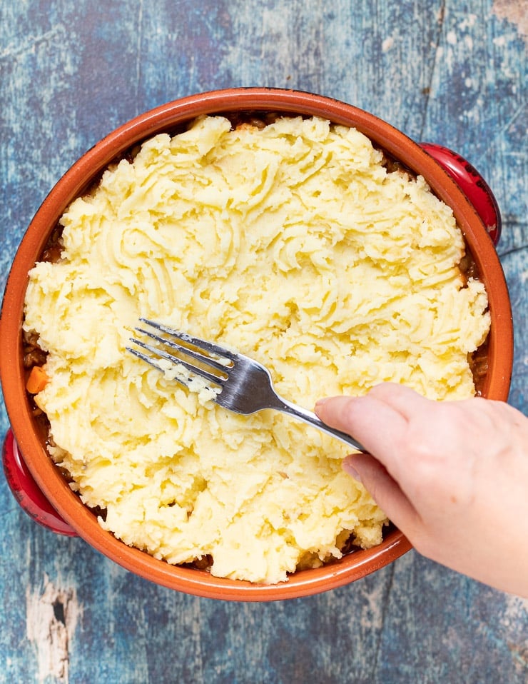 Mashed potato on Lentil Shepherd's Pie filling in a terracotta dish's Pie filling in a terracotta dish