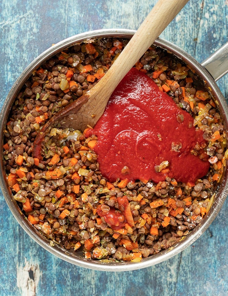 lentils, carrots, onions, garlic and crushed tomatoes cooking down in a pan 