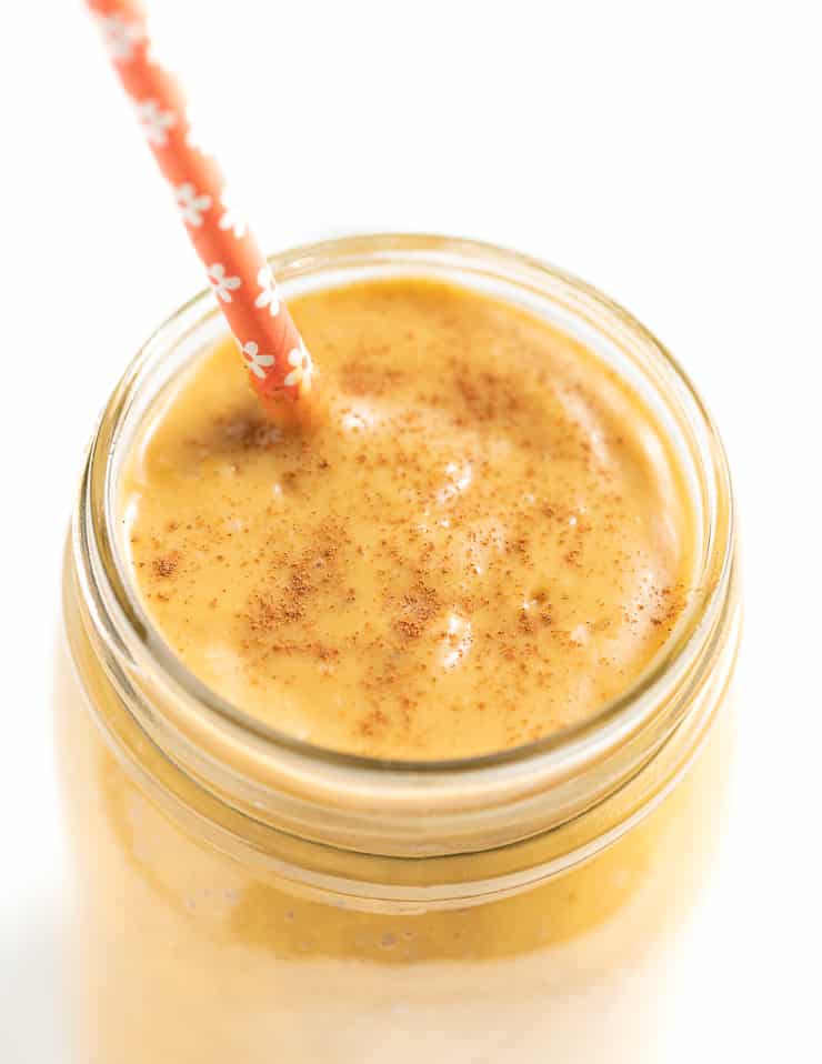 close up of the top of a smoothie in a glass with an orange flowery paper straw