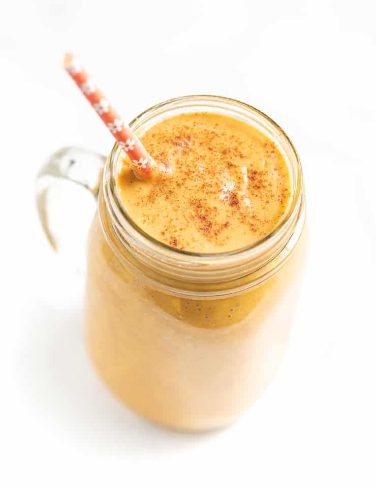 Sweet Potato Smoothie in a glass with a sprinkle of cinnamon on top and an orange paper straw 