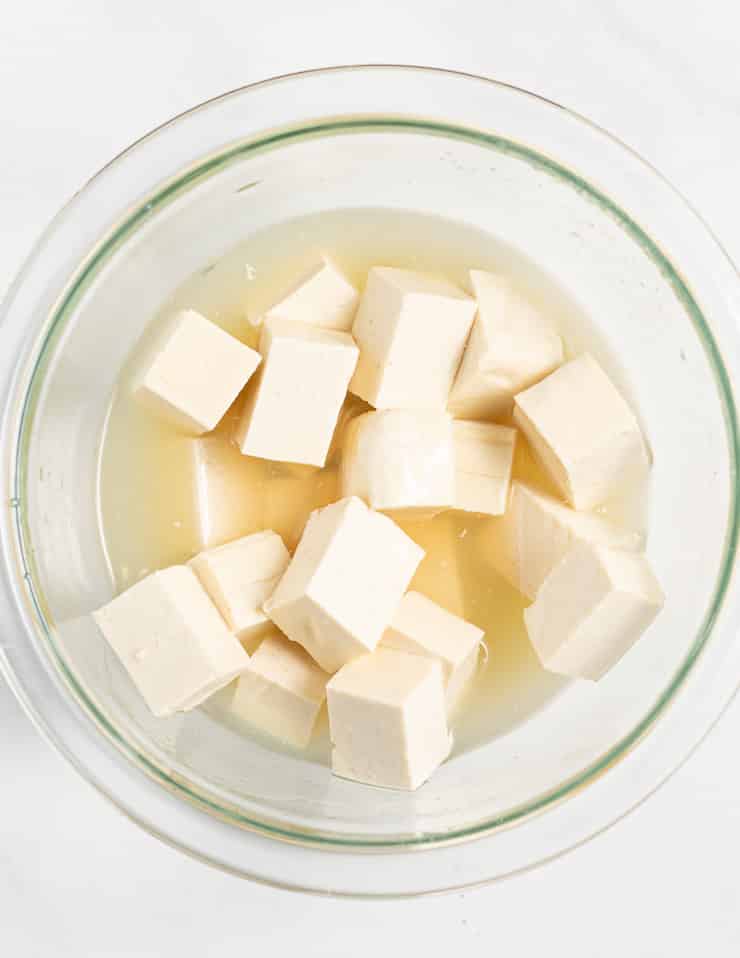 cubes of tofu submerged in a bowl of aquafaba