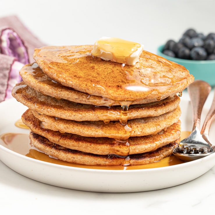 a stack of vegan spelt pancakes with butter and maple syrup