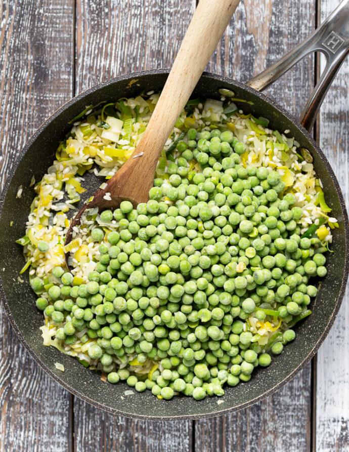 frozen peas in a pan with leeks, onions, garlic and rice