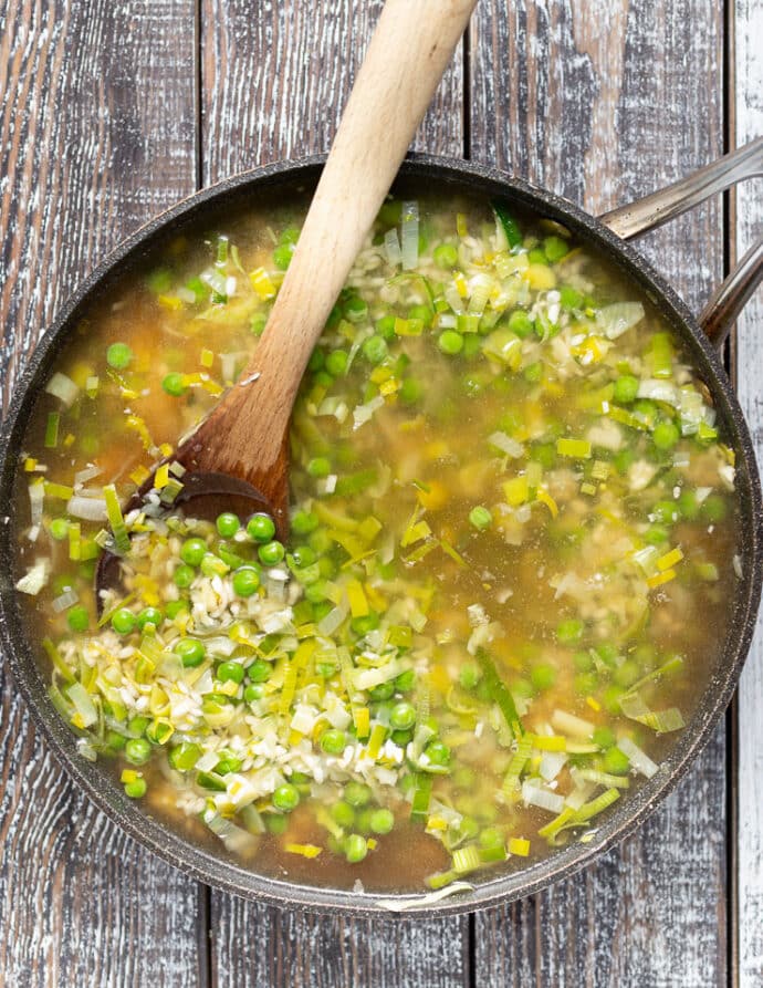 a pan of rice peas and leeks with lots of stock added