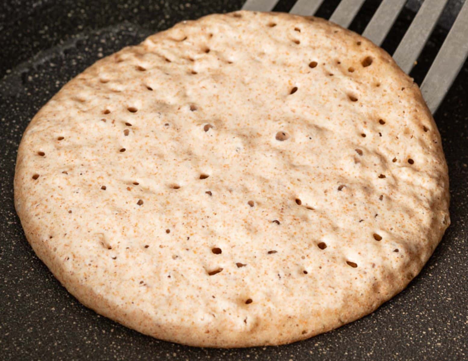 a bubbly partially cooked pancake in a pan