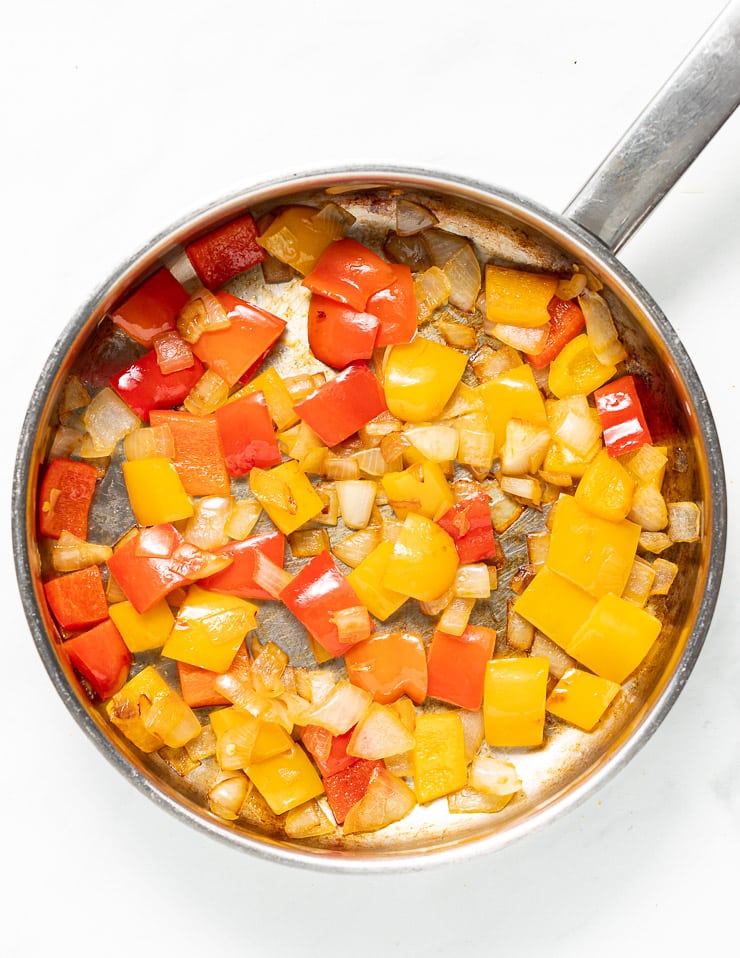 onions and bell peppers cooking in a pan