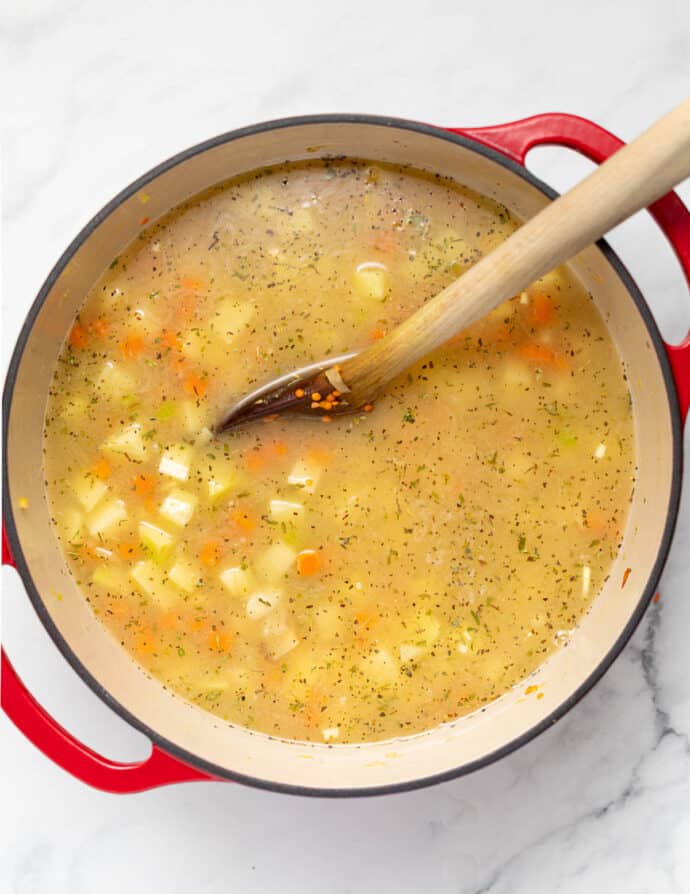 Stock added to vegetables and lentils in a large pan