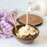 cashew milk pouring over some breakfast cereal in a bowl