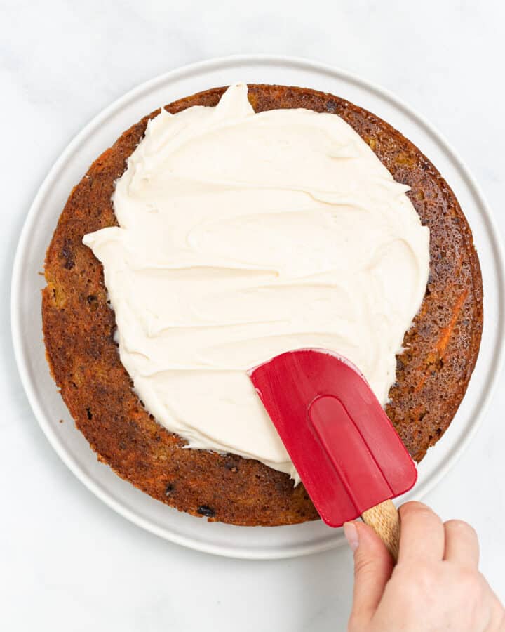 vegan cream cheese frosting being spread on a carrot cake