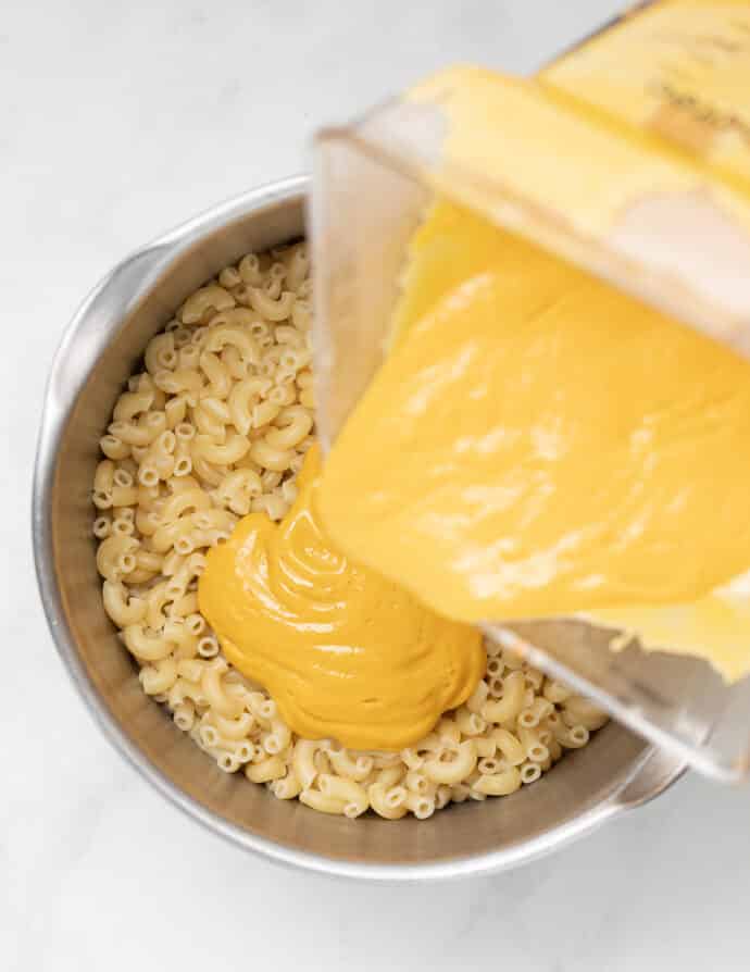 vegan cheese sauce pouring into pan of macaroni