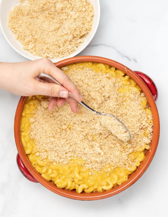 bread crumb mixture being spread on vegan mac and cheese