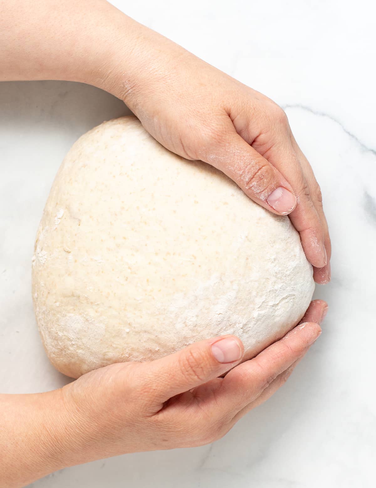 hands shaping a ball of bread dough
