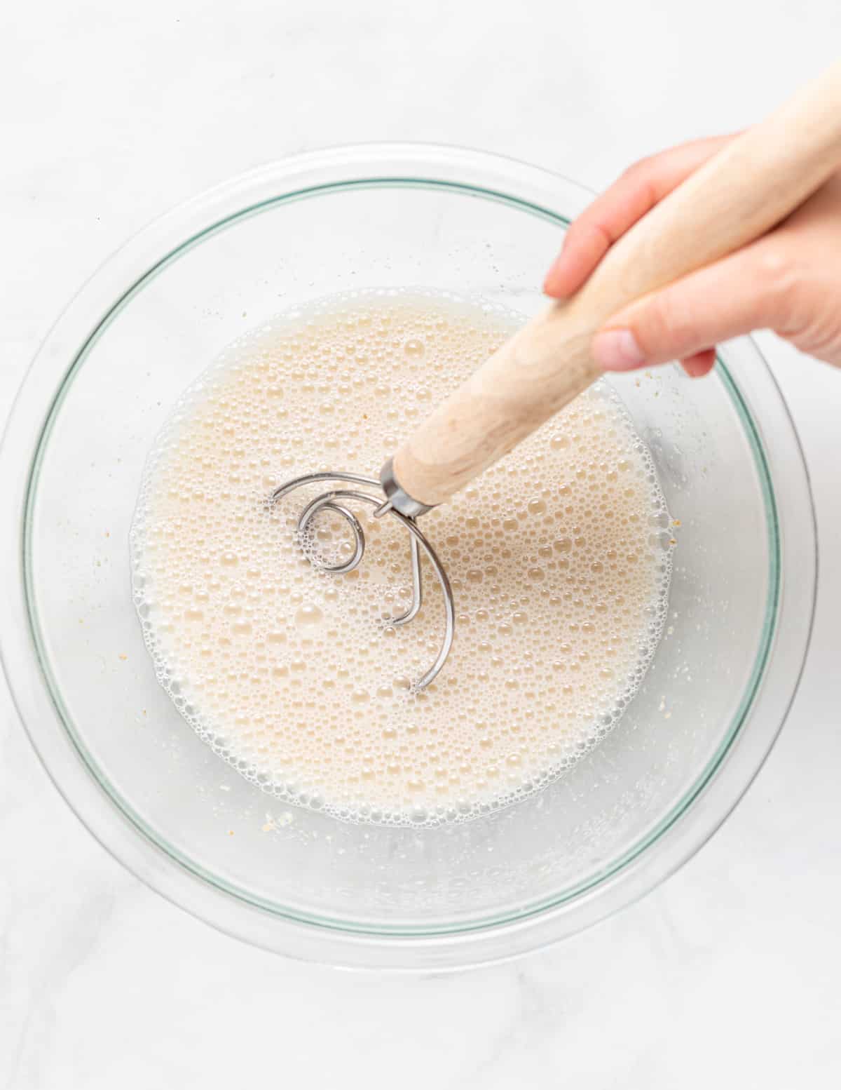 sourdough starter and water being whisked with a bread whisk