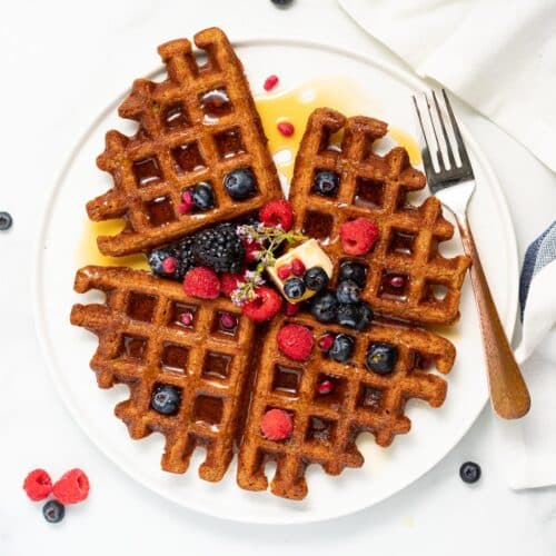 4 oatmeal waffles topped with syrup, raspberries, blackberries and blueberries