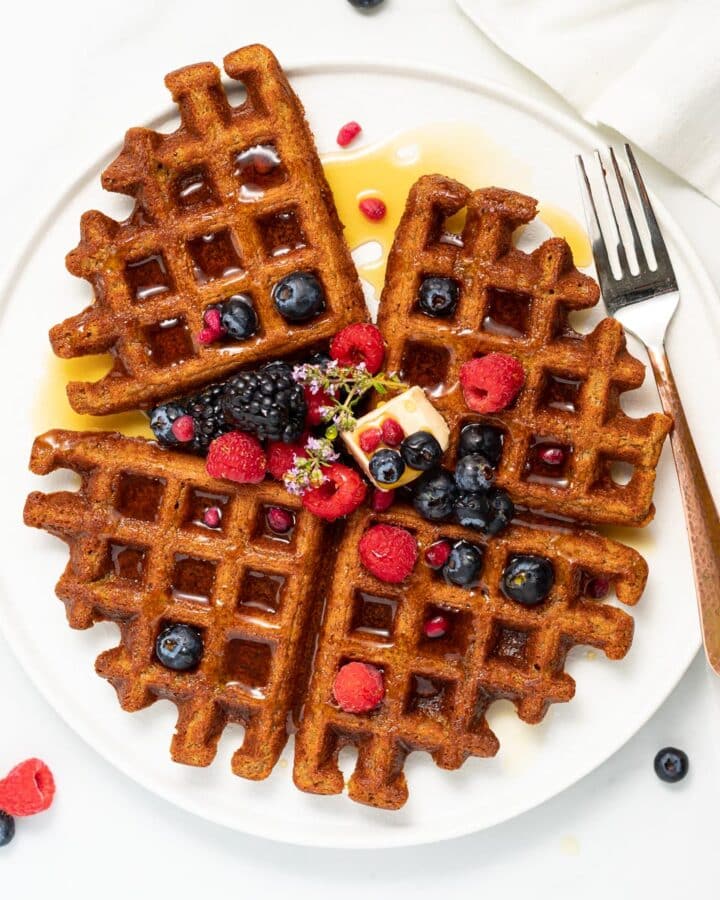 4 oatmeal waffles topped with syrup, raspberries, blackberries and blueberries