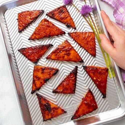 a baking tray with triangles of baked tofu and a couple of pretty chive flours