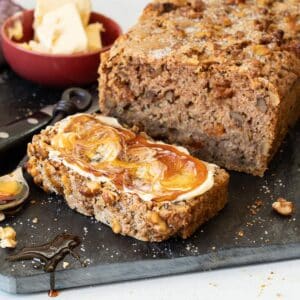 vegan zucchini bread with a slice cut off the end. Buttered and drizzled with vegan honey.
