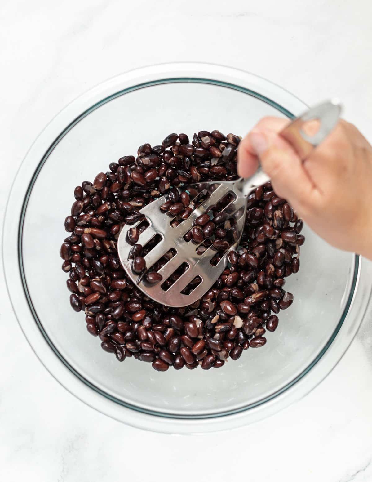 mashing black beans with a potato masher