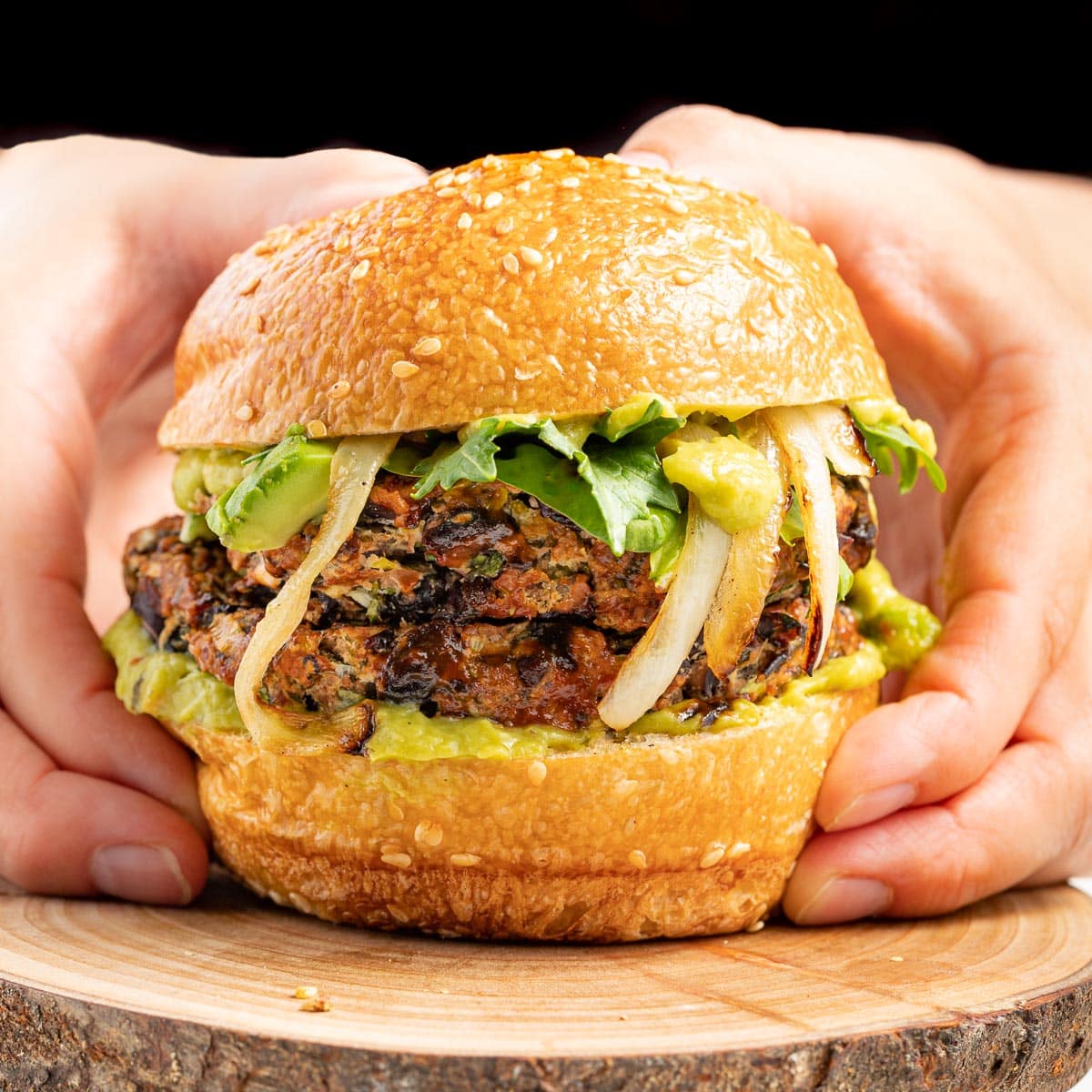 hands holding a large black bean burger