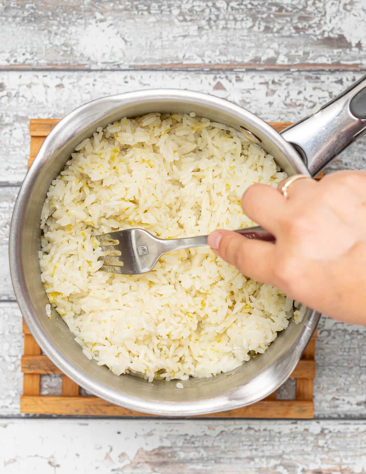 a pan of rice being fluffed up with a fork