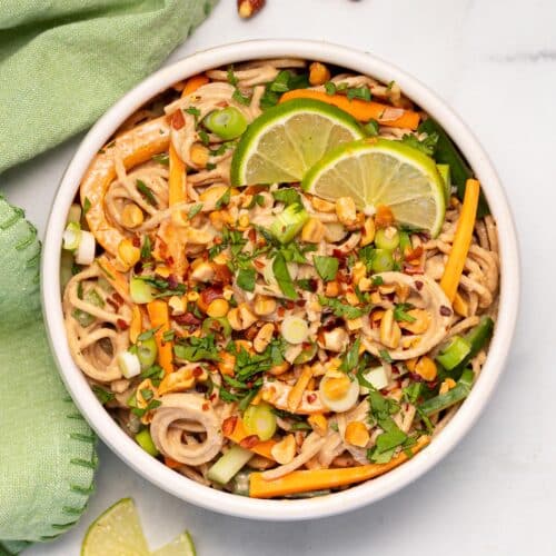 a bowl of peanut noodles with fresh vegetables and cilantro