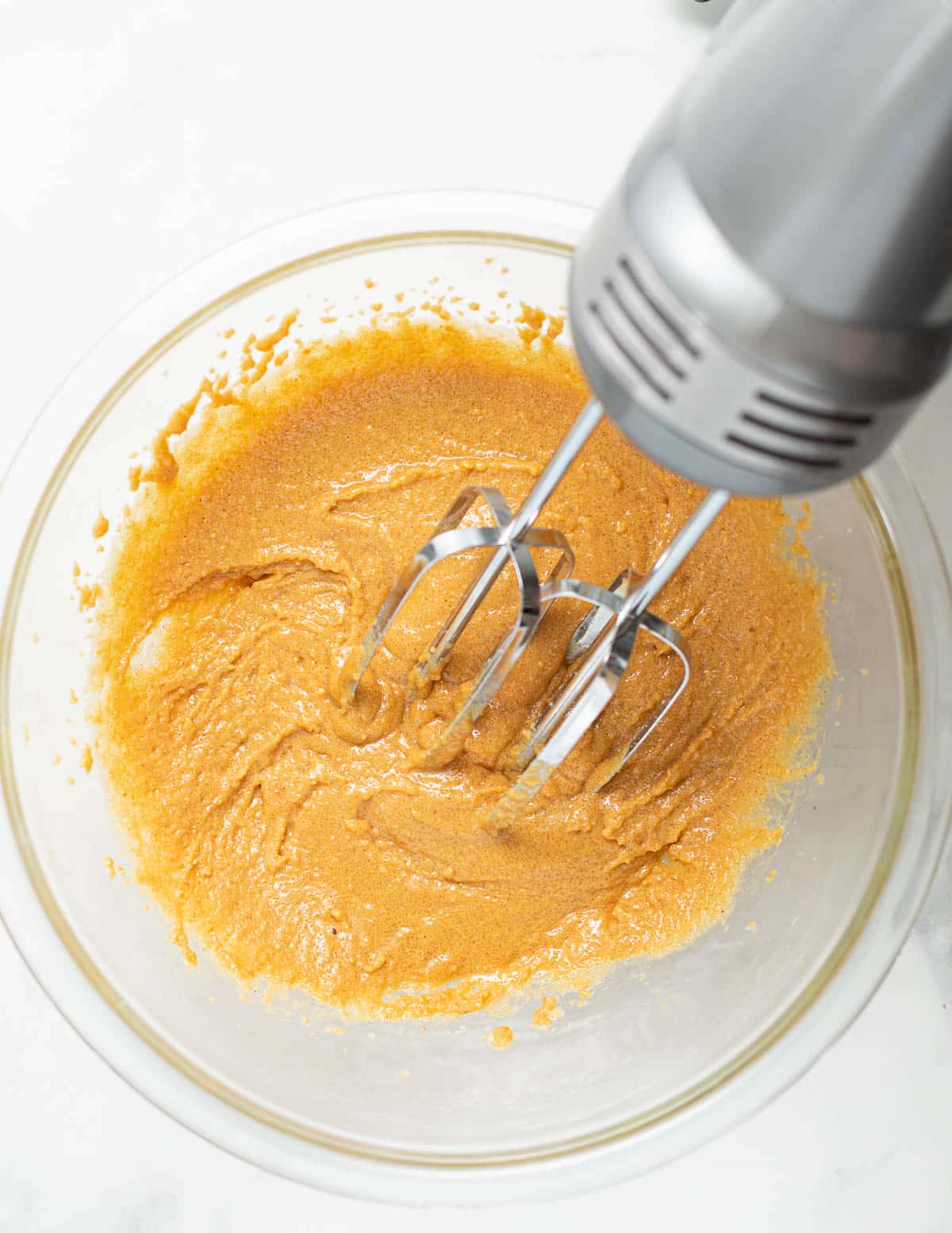 an electric hand mixer beating peanut butter and sugar together