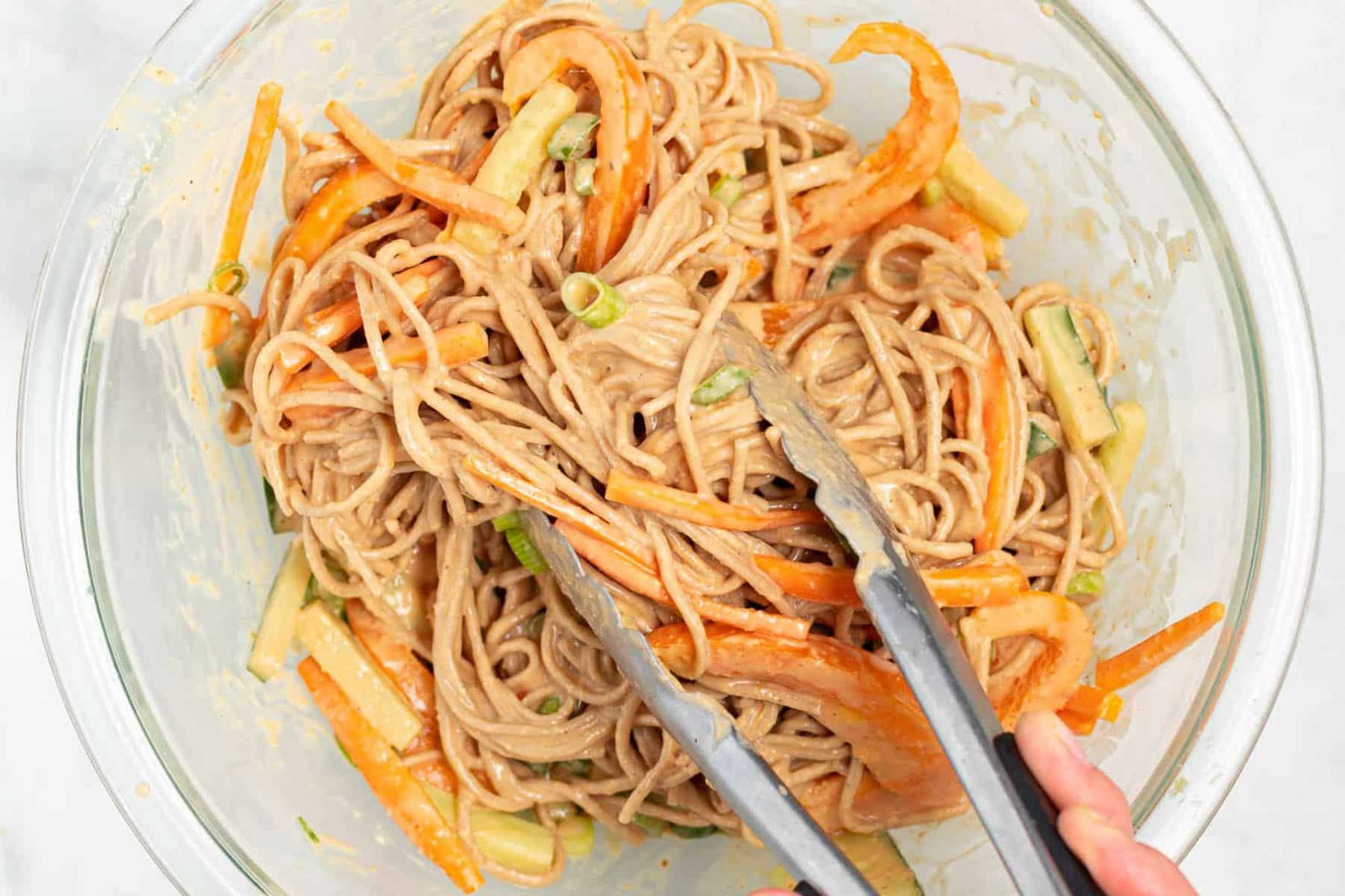 noodles tossed with peanut sauce and veggies in a bowl.