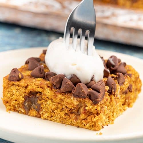 a fork being stuck into a pumpkin oatmeal bar with yogurt