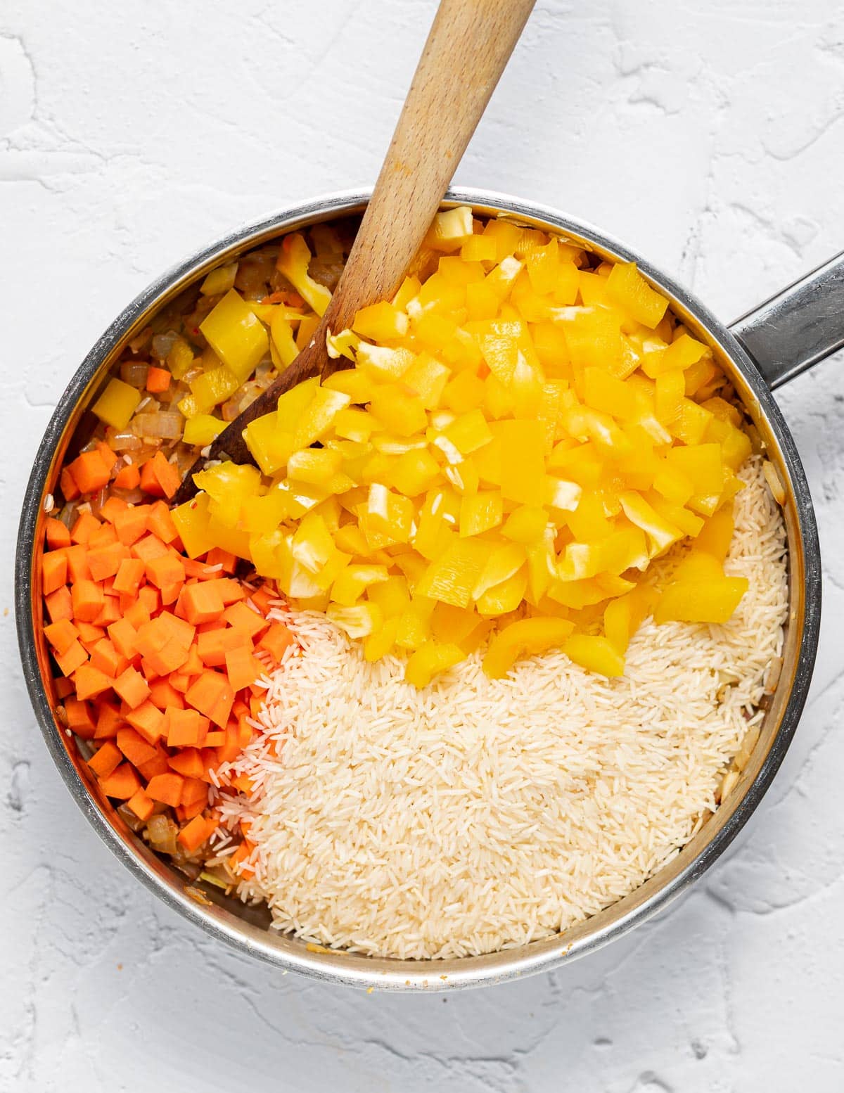 rice, onions, bell pepper and carrot in  a pan