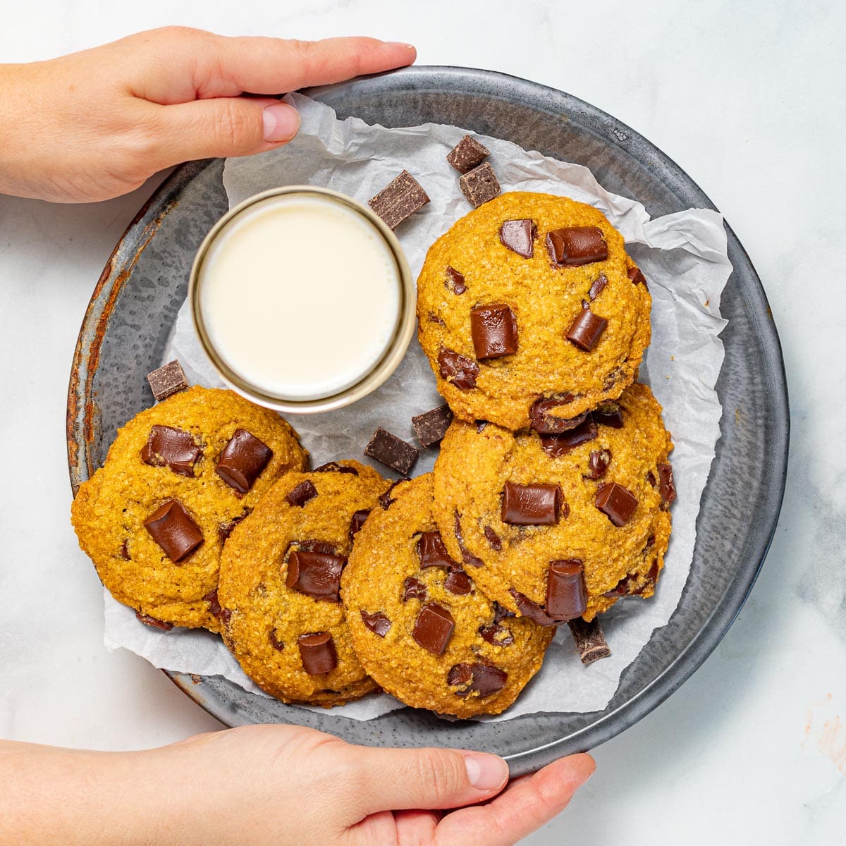 vegan pumpkin chocolate chip cookies on a tray with a glass of milk