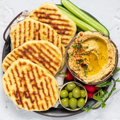 flatbreads on a platter with dip, olives and celery