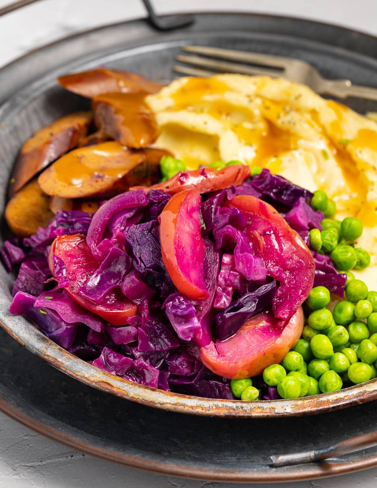 red cabbage with apples, sausage and mashed potato on a plate 