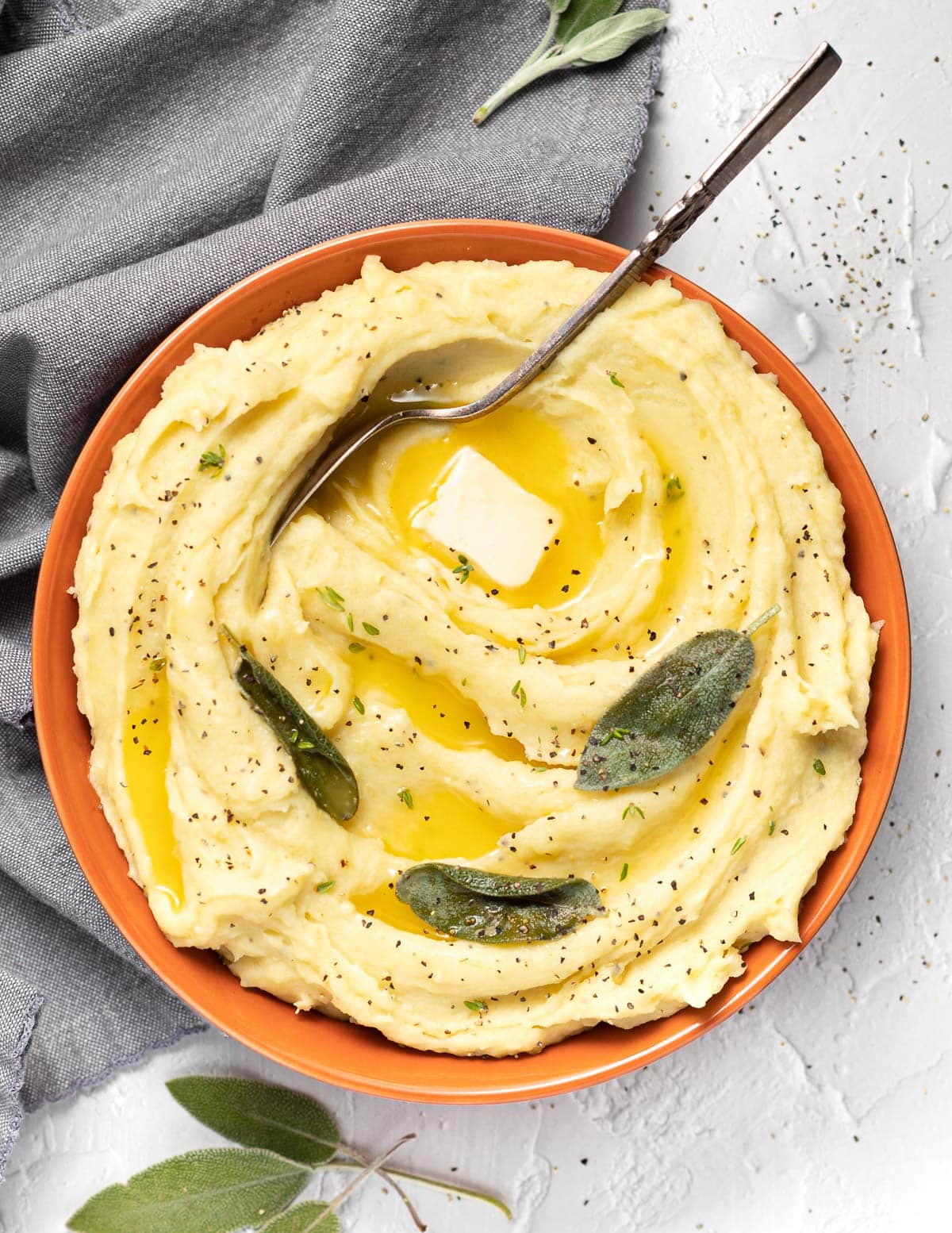 a large bowl of vegan mashed potato with melted vegan butter and sage