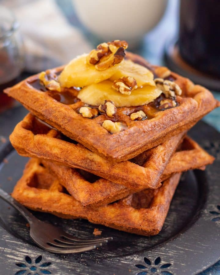 a stack of waffles topped with banana and nuts