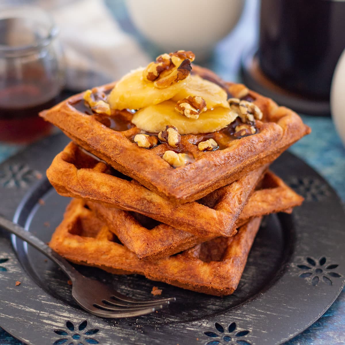 a stack of waffles topped with banana and nuts