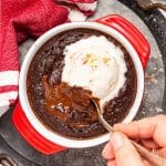 a spoon digging into a runny vegan lava cake with ice cream on top