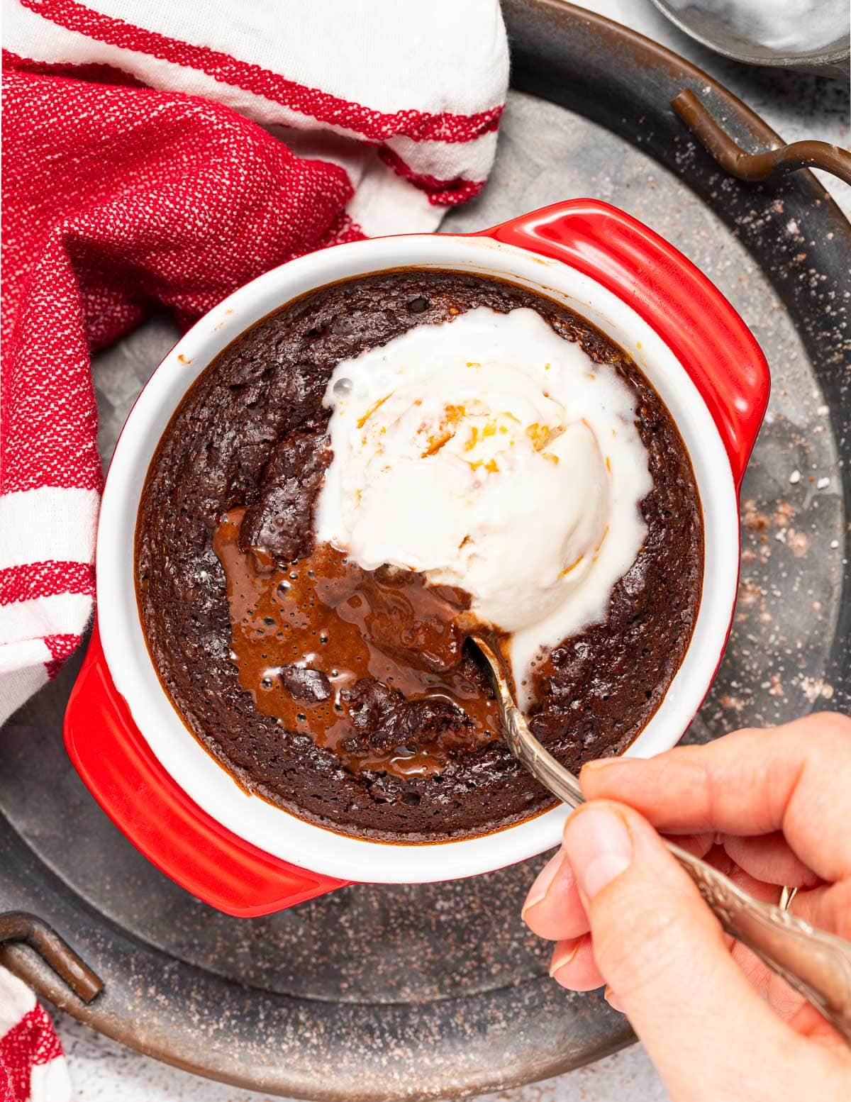 a spoon digging into a runny vegan lava cake with ice cream on top