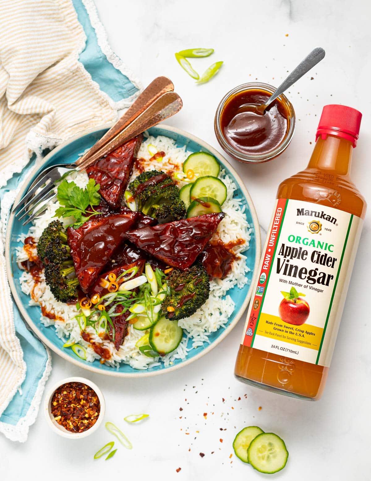 a plate of rice, broccoli and tofu next to a bottle of Marukan apple cider vinegar