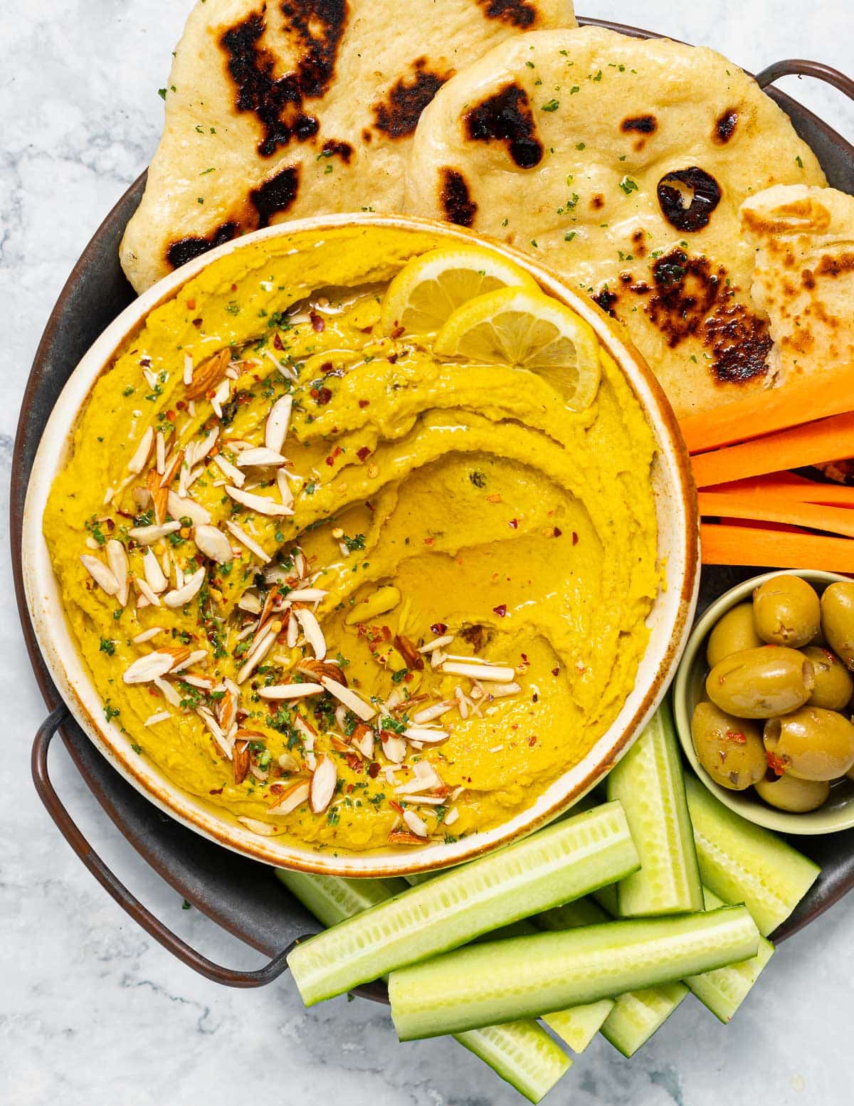 a bowl of curry hummus with flatbread and veggies