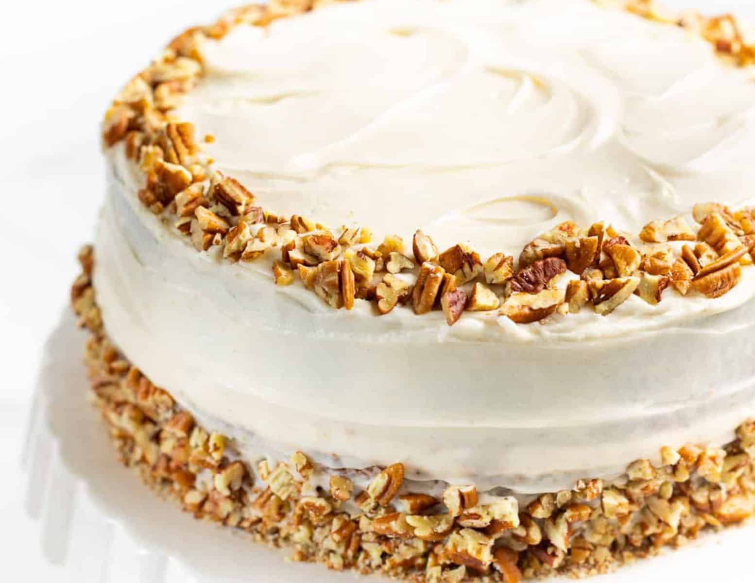 close up of a frosted cake decorated with chopped pecans. 