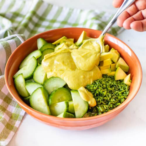 vegan avocado dressing being spooned onto a salad